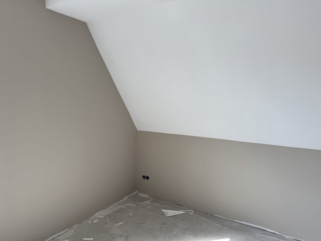 Zolderkamer met taupe wanden onder een witte schuine kap